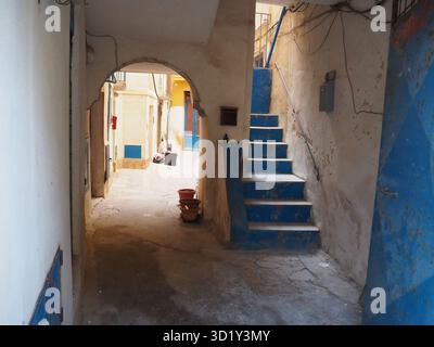 Blue painted staircase and aged passageway inside an old residential courtyard in the historic center of Trapani, featuring worn walls Stock Photo
