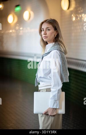 Serious businesswoman stand in office corridor with tablet, look at camera. Entrepreneur, work day Stock Photo