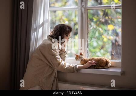 Outcast by friends teen girl feeling lonely, stresses, depressed stroking cat for emotional support Stock Photo
