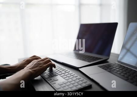 Asian man software engineer Working on Computer at office desk for writing program code IT Software Engineer finding errors tech Stock Photo