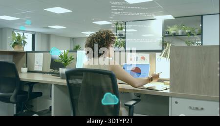 Data analyst in sleeveless blouse reviewing charts on laptop monitors at office, with code overlay Stock Photo