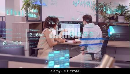 Pointing woman and leaning man analyzing financial charts at office desk, holographic overlays Stock Photo