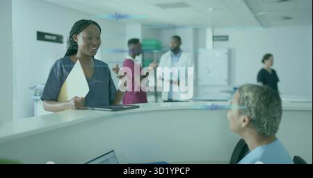 Standing female nurse holding patient folder using tablet at reception desk with laptop, copy space Stock Photo
