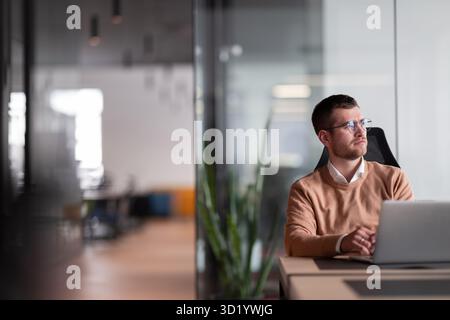 Businessman in glasses distracted from computer work look in distance thinking or pondering, thoughtful biracial male lost in th Stock Photo