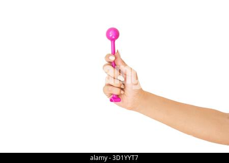 Caucasian female hand holding pink toy hammer on black background with white nail polish displayed. Stock Photo