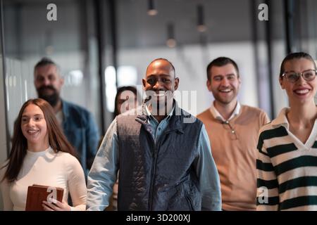 Business team in a modern open space startup office walking together. Diverse group of businesspeople smiling while having a dis Stock Photo