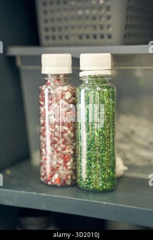 Colorful bead containers with red and green beads in clear plastic bottles Stock Photo