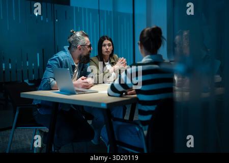 A diverse team of young professionals collaborates in a modern office conference room. Businesspeople discuss strategy, technolo Stock Photo