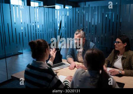 A diverse team of young professionals collaborates in a modern office conference room. Businesspeople discuss strategy, technolo Stock Photo