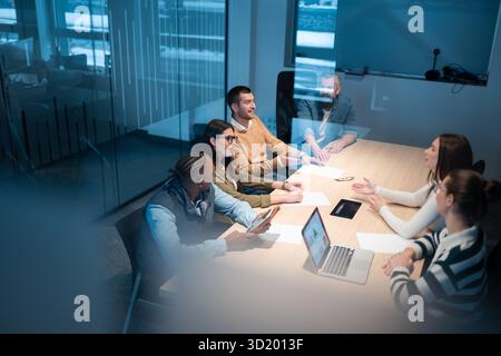 A diverse team of young professionals collaborates in a modern office conference room. Businesspeople discuss strategy, technolo Stock Photo