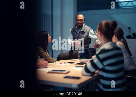 A diverse team of young professionals collaborates in a modern office conference room. Businesspeople discuss strategy, technolo Stock Photo