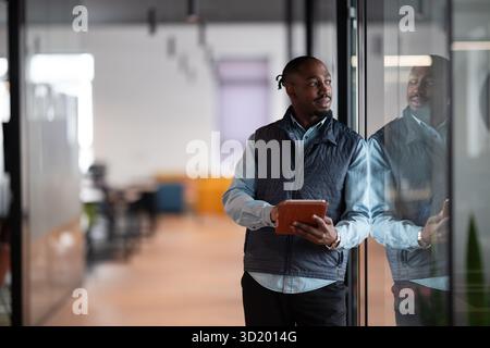 A confident, mature businessman in his 40s-50s using a tablet in a modern office. He is engaged in digital finance management, l Stock Photo