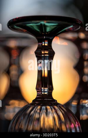 Closeup of an upturned faceted wine glass illuminated by sunset light Stock Photo