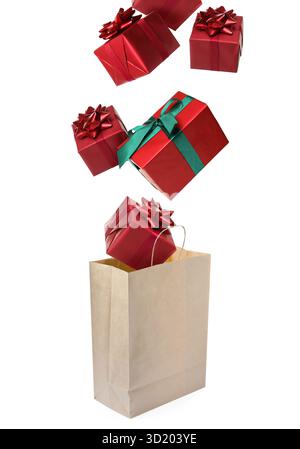 Many gift boxes falling into paper bag on white background Stock Photo