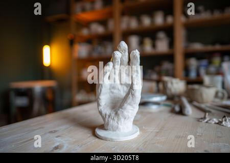 Pottery workshop with clay hand palm on table, bespoke piece of modern art an unusual ceramic stand Stock Photo