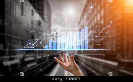 A hand reaches out towards a digital bar graph and growth chart, illuminated by sunlight in an urban setting, representing data visualization and busi Stock Photo