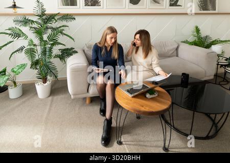 Two women collaborating on a project in a modern indoor workspace during the day Stock Photo