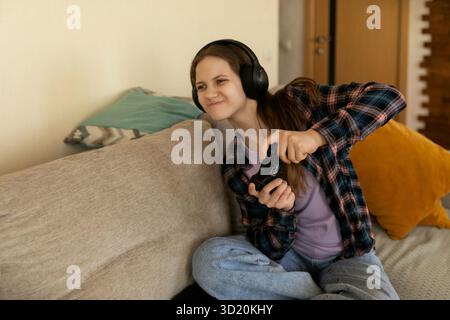 Young woman enjoying gaming session at home while sitting on the sofa in cozy living room Stock Photo
