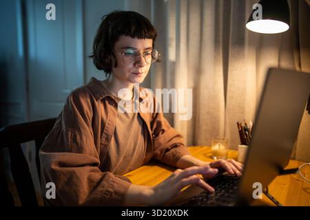 Stressed exhausted woman working late. Tired female typing on laptop night hours in stress at home Stock Photo