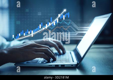 A close-up view of hands typing on a laptop featuring financial graphs and data visualizations representing growth and analysis in a modern workspace. Stock Photo