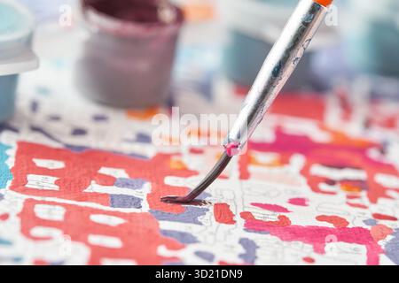 Close up of paintbrush on colorful paint by numbers canvas with blurred paint Stock Photo