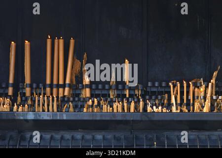Burning candles on metal candleholder stand in catholic church Stock Photo