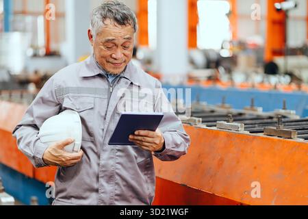 Professional senior engineer, Japanese expert engineer male happy working in heavy industry production line monitor check Stock Photo