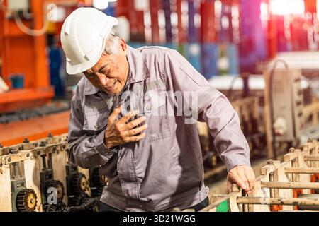 Senior factory worker chest pain suffering from heart attack, heart fail sign expression at work Stock Photo