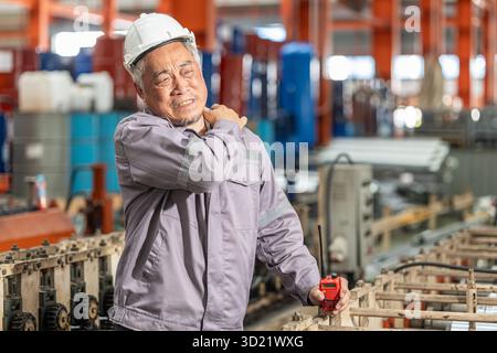 Senior worker tired exhausted muscle pain, Suffer from shoulder pain from hard work in heavy industry factory. Stock Photo