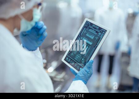technician worker using tablet in food and drinks factory, Pharmaceutical plant monitor control inspecting production line Stock Photo