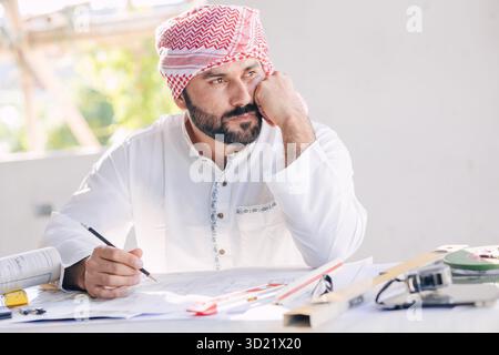 Arab construction engineer architect, Muslim builder working at desk at construction site design floor plan thinking idea Stock Photo