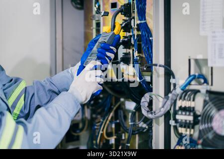 Electrician worker checking repair maintenance fix service electric system. engineer testing electric cable at main power line cabinet fuse box. Stock Photo