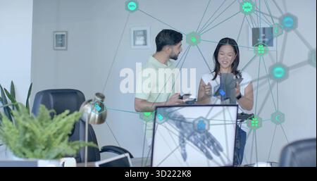 Gesturing business casual coworkers using smartphone and tablet in office with robotic hand graphic Stock Photo