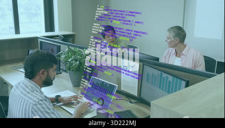 Typing Indian developer tapping laptop keyboard in office, with monitors, coffee cup, mouse, plant Stock Photo