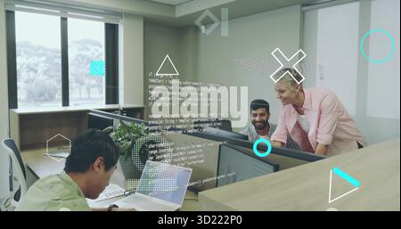 Collaborating software developers reviewing code in open-plan office, with monitors and laptop Stock Photo