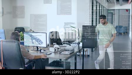 Mid-adult woman observing dual monitors showing 3D robotic hand model at office desk, VR headset Stock Photo