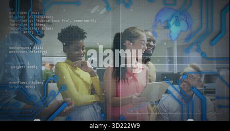 Collaborating team reviewing project on tablet in open-plan office, with laptop and smartphone Stock Photo