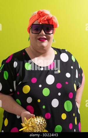 Smiling woman in oversized sunglasses holding golden pineapple Stock Photo