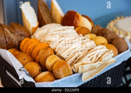 Assortment of freshly baked breads, lunch rolls and pretzels in a Plastic Rattan Basket for appetizer or meal starter. Stock Photo
