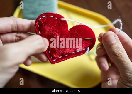 Stitching a red heart shape Stock Photo
