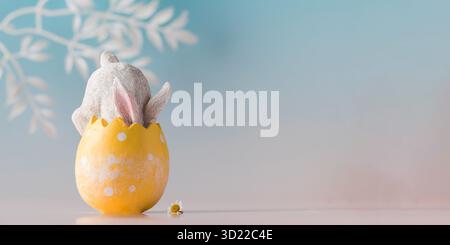 Banner a white rabbit hid in an Easter egg on a blue background. Festive Easter card. Copy space. Stock Photo