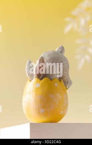 A white rabbit hid in an Easter egg on a yellow background. Festive Easter card. Stock Photo