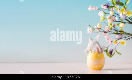 A white rabbit hid in an Easter egg on a blue background. Festive Easter card. Copy space. Stock Photo