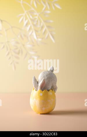 A white rabbit hid in an Easter egg on a yellow background. Festive Easter card. Stock Photo