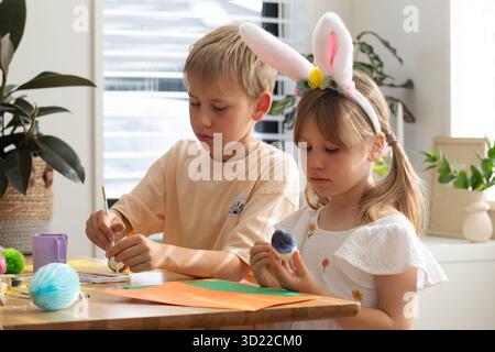 Children painting colorful easter eggs with joy and creativity at home. Easter Stock Photo