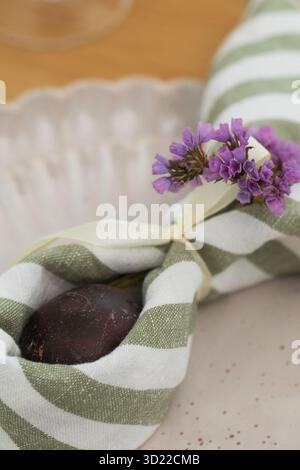 Easter egg wrapped in linen napkin in the shape of bunny with ears. Happy Easter Stock Photo