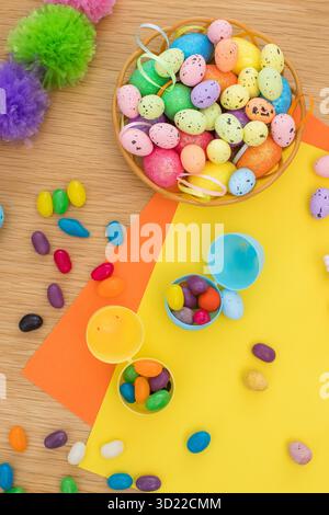 Bright background with candies in the form of Easter eggs in plastic eggs. Egg hunt concept. Happy Easter. Top view. Stock Photo