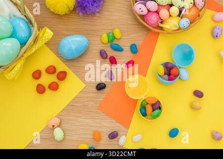 Bright background with candies in the form of Easter eggs in plastic eggs. Egg hunt concept. Happy Easter. Top view. Stock Photo