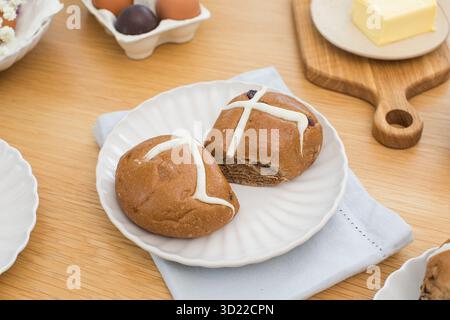 Hot cross buns on white plate on wooden table. Happy Easter Stock Photo