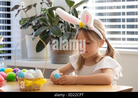 Girl with bunny ears holding plastic Easter egg with surprise inside. Egg hunt. Happy Easter. Stock Photo